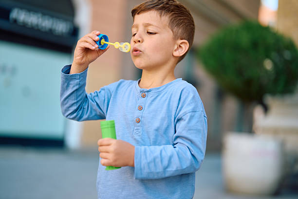 Young boy blowing soap bubbles in the city center