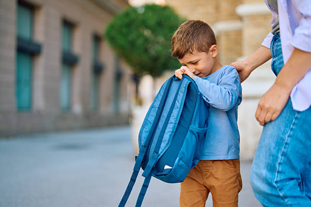 Shy elementary school child hiding behind a backpack while walking to school with a parent, capturing the essence of the back-to-school journey and family support