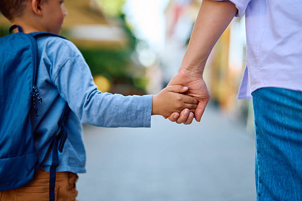 istock Child going to school holding parent's hand 2218444717