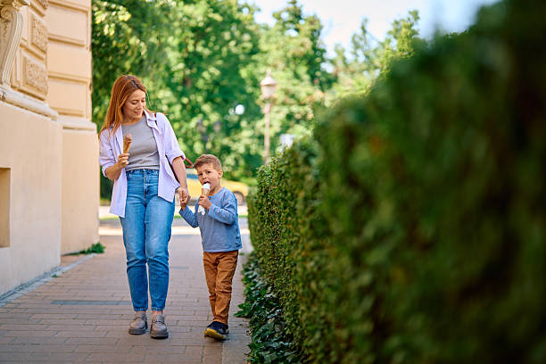 istock Mother and son enjoying ice cream while walking down the street 2218444845