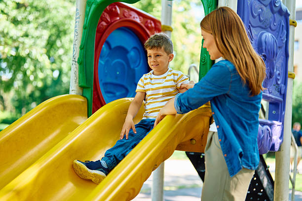 istock Mother helping her son going down the slide at the playground 2218445116