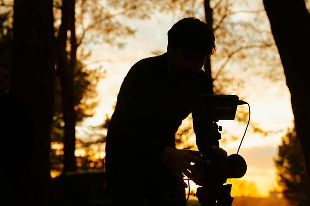 Silhouette of Cameraman Adjusting Camera in Sunset Forest Scene