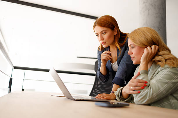 istock Two businesswomen are working together, analyzing data on a laptop in a modern office environment 2218449521