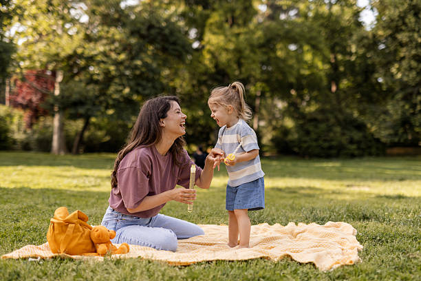 istock Smiling Mom and Toddler Enjoy Bubble Play in Park 2218452877