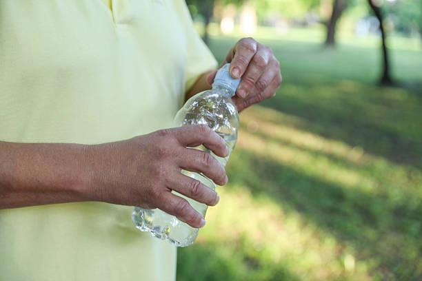 Man Holding a Plastic Bottle of Water in a Park