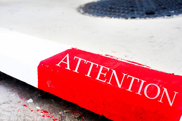 Letters Attention on red sidewalk border stone
