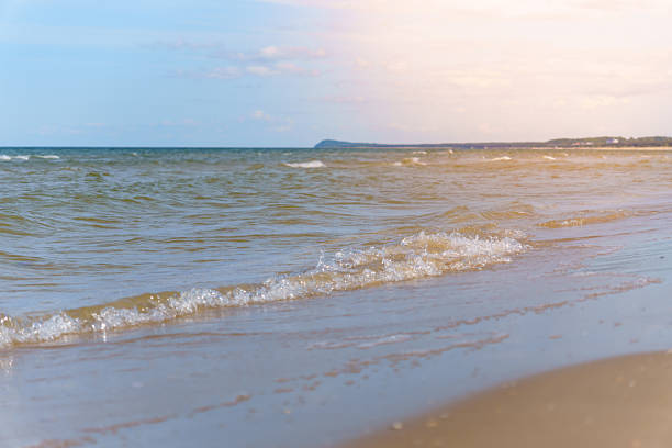 Ocean waves gently lap on the sandy shore under a blue sky with sparse clouds Serene coastal landscape for peaceful relaxation