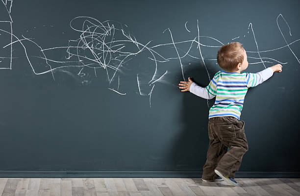 istock A toddler draws with chalk on a large black wall 2218458125