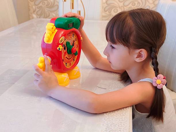 Little girl learning clock by toy . High quality photo