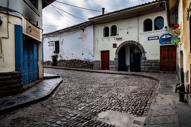 Cobblestone plaza with benches and colonial buildings. Historic town square under cloudy sky. Picturesque travel destination with traditional architecture.