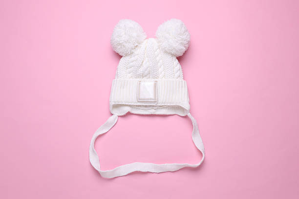 Children's warm hat with a balabons on a pink background