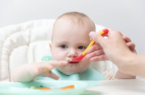 istock Mom feeds baby with a spoon 2218469638