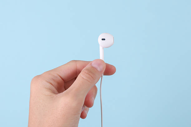 istock Female hand holding wired headphone on blue background 2218470961
