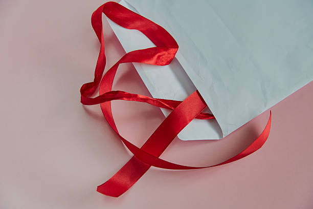 A red ribbon peeking out from a large white envelope on a pink background