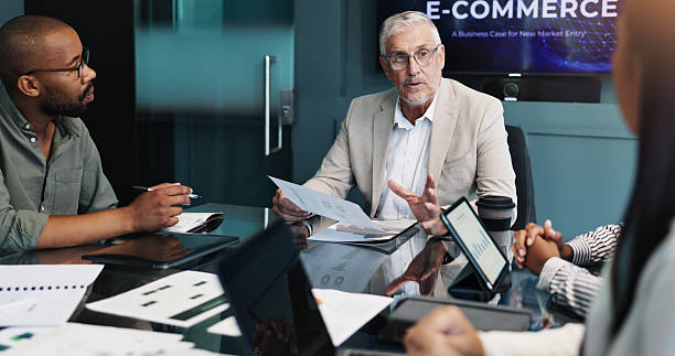 istock Meeting, group and collaboration for ideas, boardroom and plan for marketing strategy with graphs. Business, brainstorming and people with tech for customer trends, ecommerce and paperwork with stats 2218477035