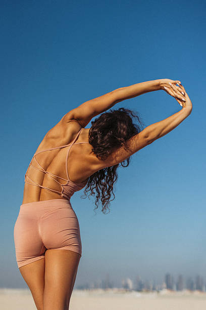istock Woman stretching outdoors in activewear under a clear blue sky background 2218477205