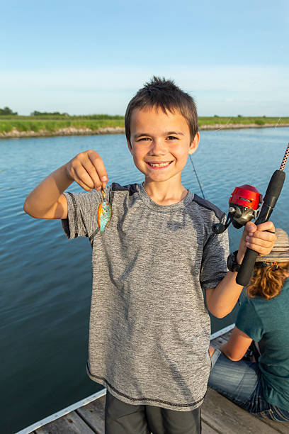 istock Boy Holding Small Sunfish He Caught While Fishing 2218479029