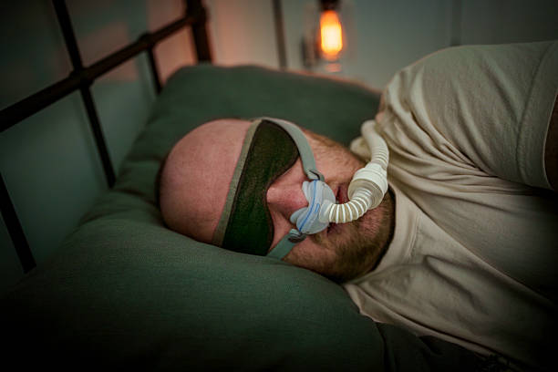 istock Young Male Patient Undergoing CPAP Therapy for Obstructive Sleep Apnea While Resting in Bed Wearing Nasal Interface and Sleep Mask 2218479746