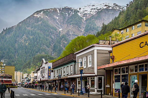 View of downtown Juneau, Alaska, on overcast spring day with people walking, talking and shopping; mountains in background