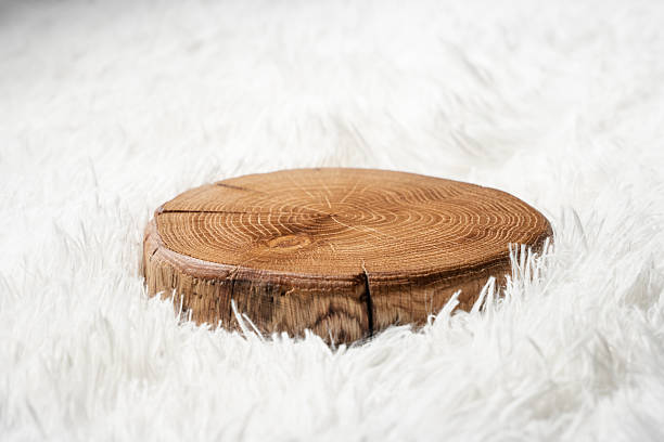 Round Wooden tree slice, cutting board laying on a white fluffy textile background
