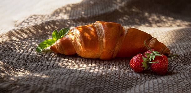 istock Golden croissant on rustic burlap with mint sprig, natural light 2218483216