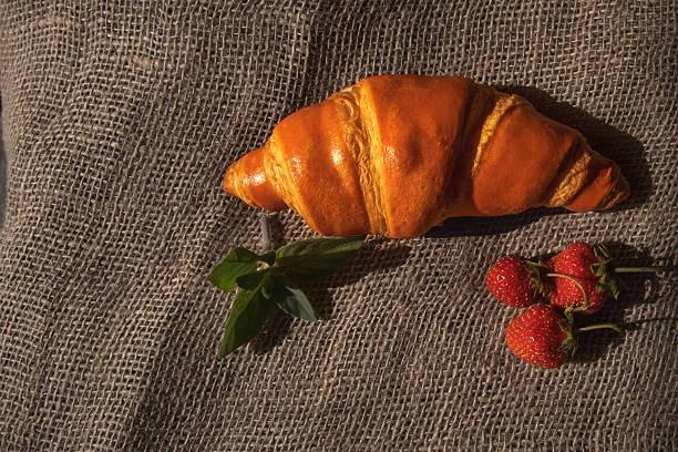 istock Golden croissant on rustic burlap with mint sprig, natural light 2218483226