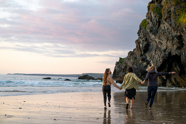 Friends have fun on beach at sunset, Cornwall