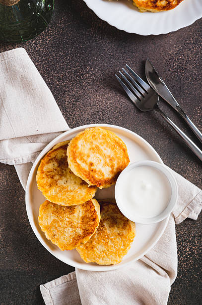 Appetizing potato fritters and sour cream on a plate on the table top and vertical view