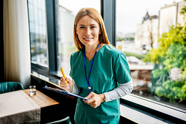 istock Smiling nurse holding clipboard and pen by the window 2218483725