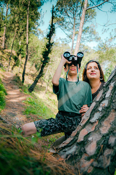 istock Mother and son birdwatch together in pine forest. 2218486172