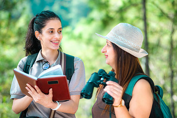 istock Women smile at each other while birdwatching in the forest. 2218486206