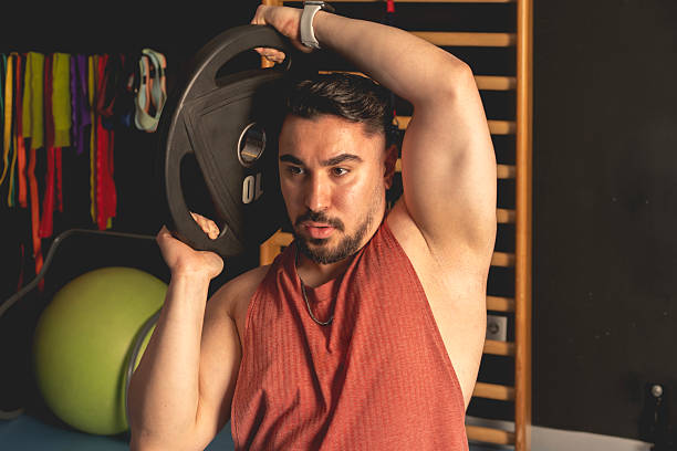 istock Muscular bodybuilder guy doing exercises in gym, rubber flange plate 2218487001