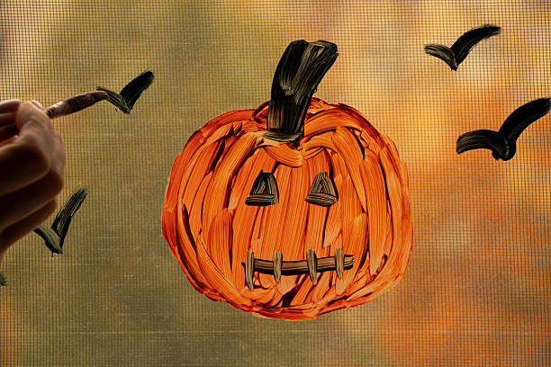 Pumpkin drawing on window as Halloween decoration in apartment with autumn background