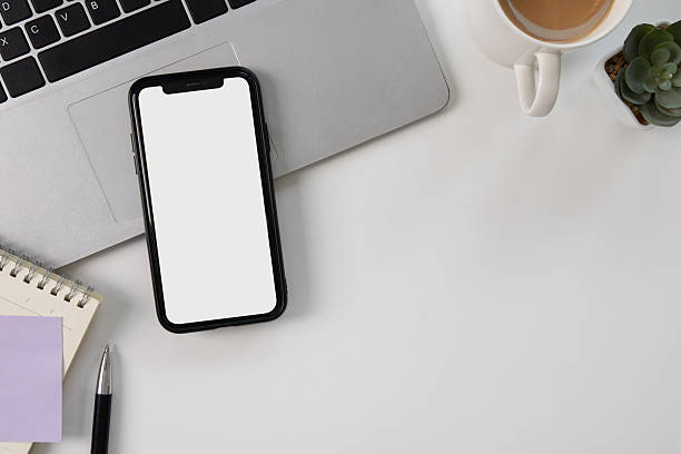 White mockup screen of mobile phone on white desk, top view