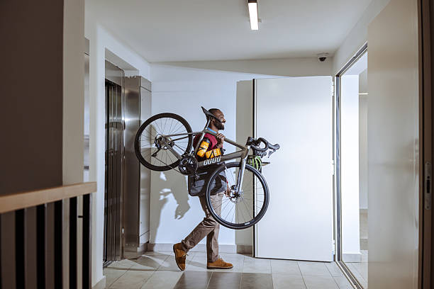 istock Urban commuter carrying bicycle through modern building hallway 2218490389