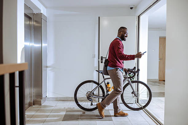 istock Man walking indoors pushing a bicycle and smartphone in a modern building 2218490399