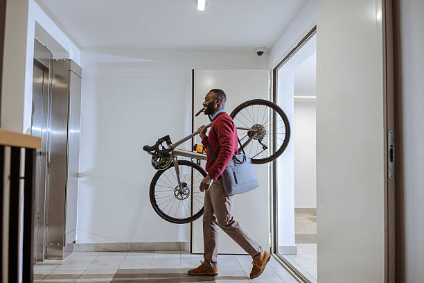 istock Urban commuter carrying bicycle through modern building hallway 2218490449