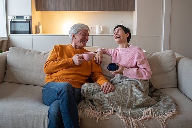 istock Laughing happy relaxed mature couple enjoying tea on couch while talking sharing during weekends 2218492440