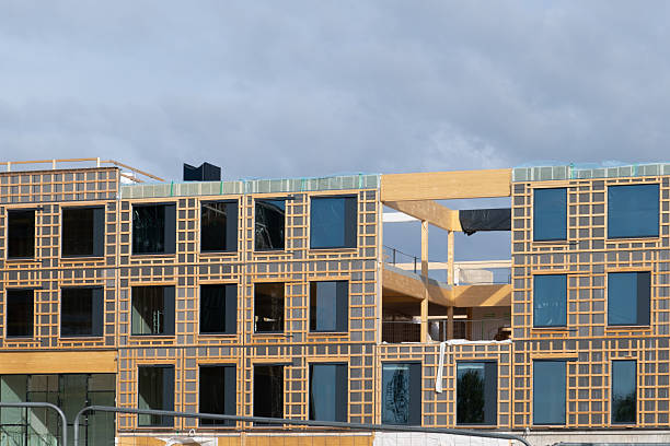 Modern building under construction shows wooden grid facade and large glass windows
