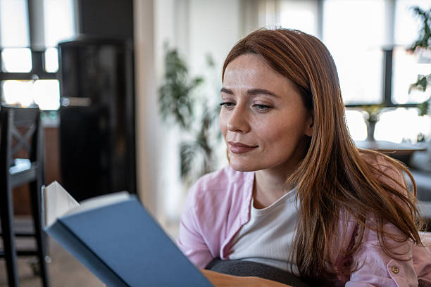 istock Young woman reading a book at home and smiling 2218496213
