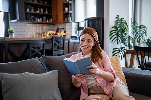 istock Young woman relaxing at home reading a book 2218496248