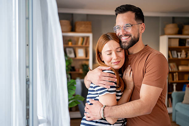 istock Happy young couple embracing at home by the window 2218499229
