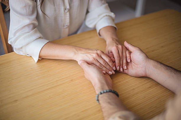 istock Couple holding hands over wooden table, showing support and love 2218501578