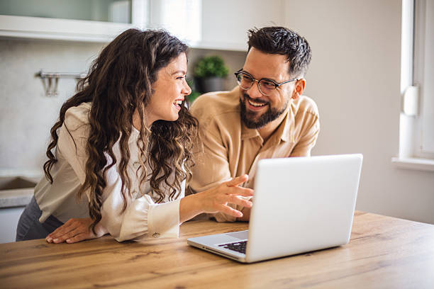 istock Happy couple smiling and using laptop in kitchen 2218501754