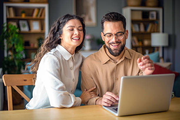 istock Young couple laughing and having fun while using laptop at home 2218501819