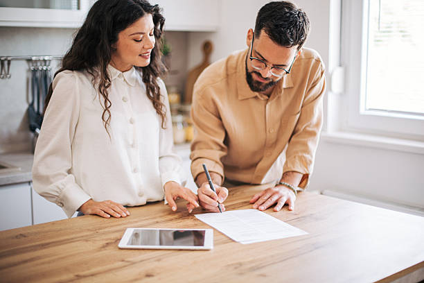 istock Young couple signing a contract in their kitchen using a digital tablet 2218501979