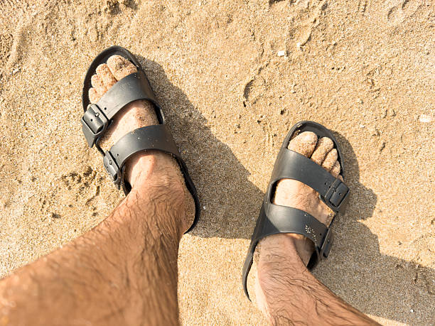 istock Tourist walking on sandy beach wearing black sandals 2218505403