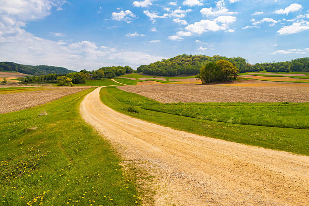 istock Scenic Road Through Green Farm Field 2218506643