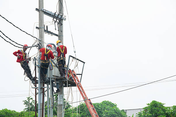 Technician works in a bucket high up on a power pole.