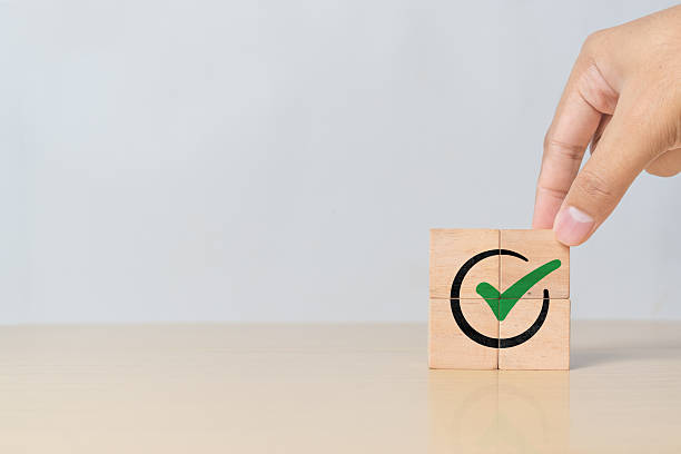 istock Tick mark icon on cube block being assembled by hand. Symbol of project approval, certified documents, and quality control process 2218522684